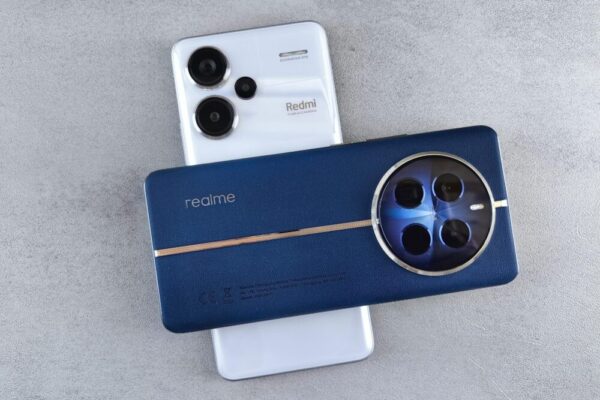 realme 12 Pro 與 Redmi Note 13 Pro 對比:規格與價差全覽 Close-up view of Realme and Redmi smartphones placed on a grey textured surface, showcasing modern technology design.