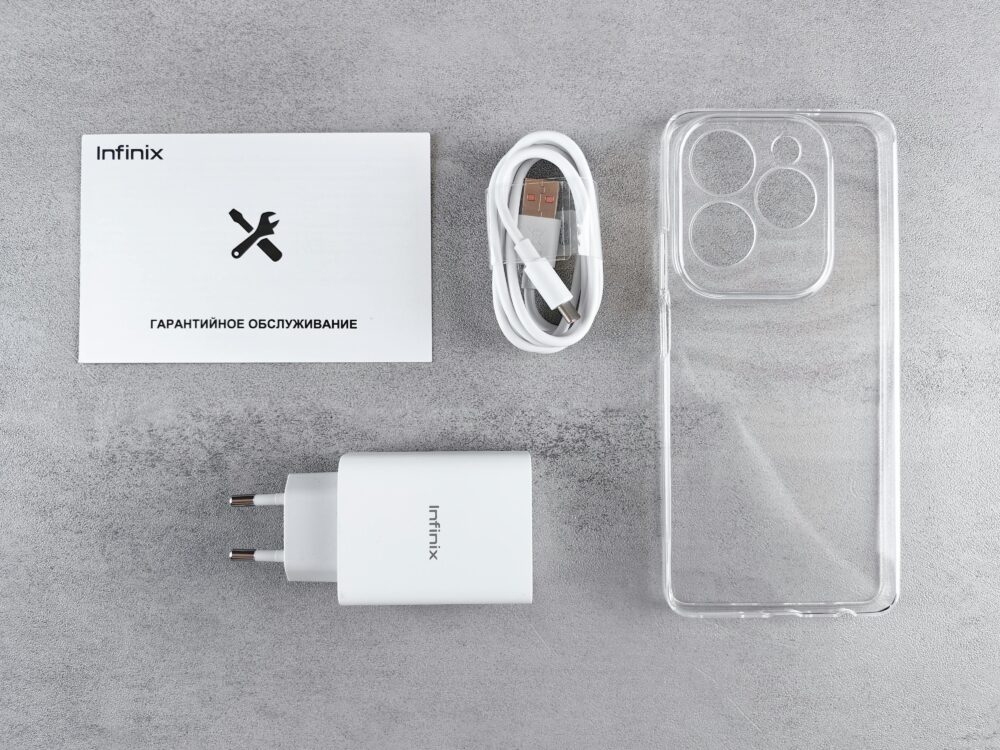Flat lay of Infinix smartphone accessories with charger, cable, case, and warranty card.