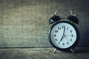 經典黑色模擬鬧鐘置於鄉村木質背景，適合時間與懷舊主題
