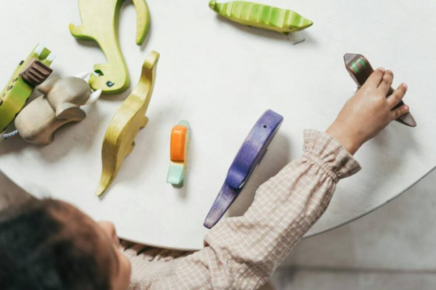Child playing with colorful wooden toys in a playful indoor setting.