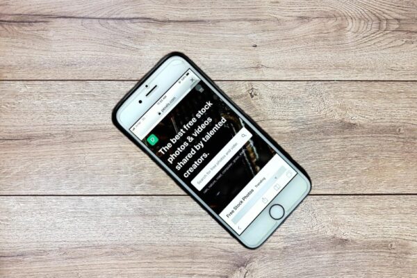 Top view contemporary mobile phone with opened website on screen placed on wooden table