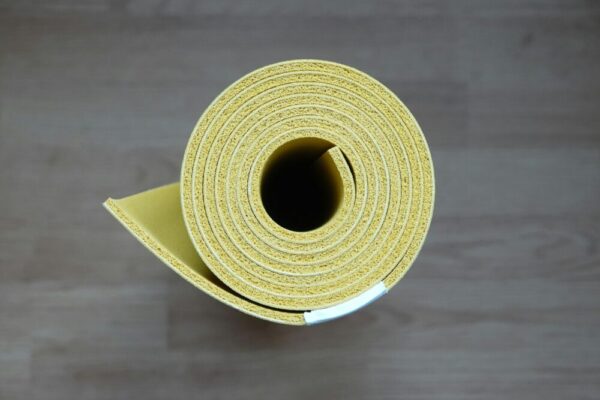 Close-up of a rolled yellow yoga mat, ideal for fitness enthusiasts and interior design.