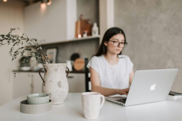Focused woman working remotely from home using a laptop. Cozy, modern interior with natural elements.