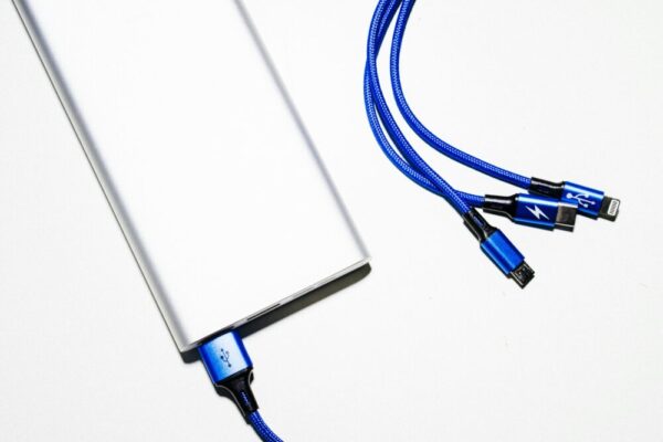機場充電樁安全要點與自備電源建議:手機與筆電長途旅程充電攻略 Minimalist image of a power bank with blue USB charging cables on a white background