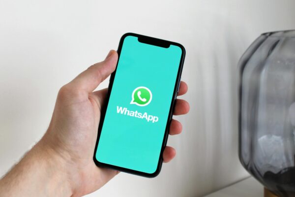 最好用的10款免費手機應用程式(2025精選, iOS與Android指南) Close-up of a hand holding a smartphone displaying the WhatsApp app screen.