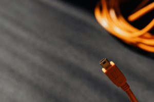充電很慢或充不進去解法:線材、插頭、快充協議一步步排查 Macro shot of an orange USB cable connector on a textured surface with soft shadows.