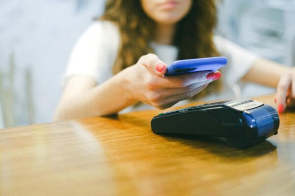 A woman processes a contactless payment using her smartphone at a payment terminal.