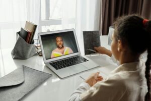 A young girl participates in an interactive online class with a teacher on a laptop, fostering education from home.