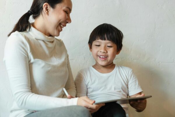A happy mother and child enjoying quality time together with a tablet indoors.
