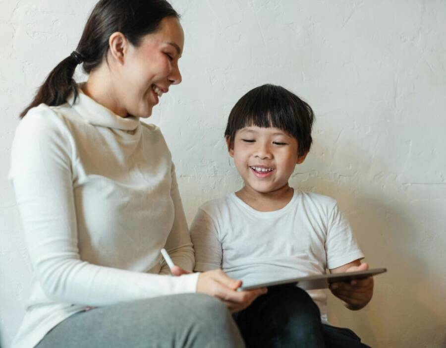 A happy mother and child enjoying quality time together with a tablet indoors.