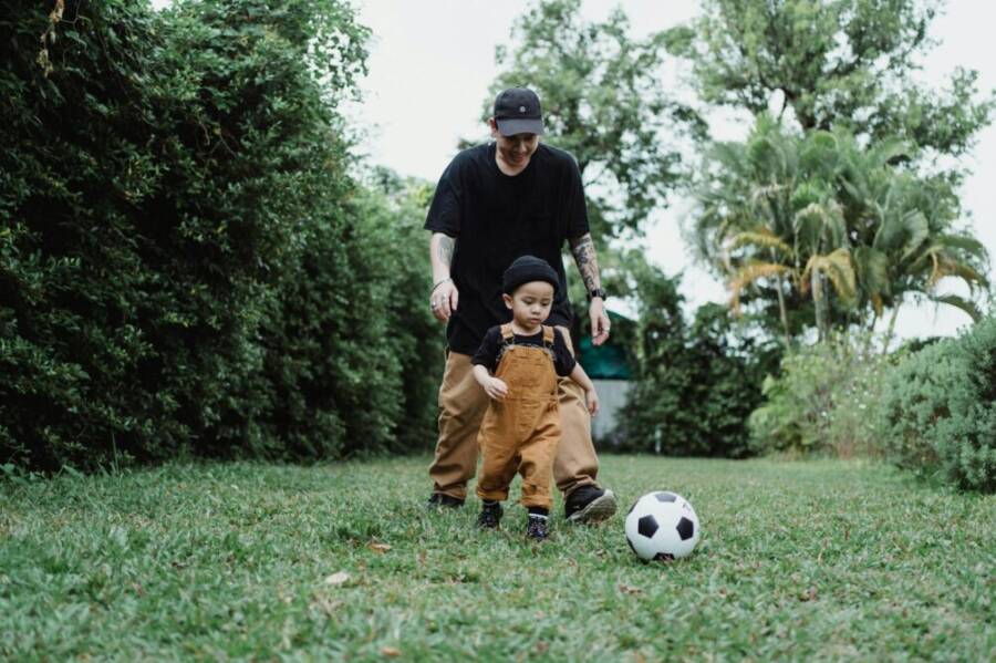 A father and son enjoying a playful game of soccer together in the backyard.