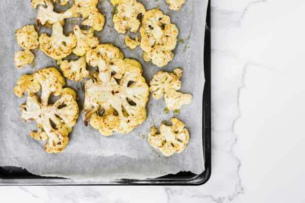 Delicious roasted cauliflower florets on a baking tray, healthy and keto-friendly.