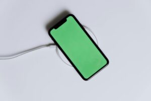 A minimalist smartphone with a green screen on a wireless charger, ideal for tech mockups