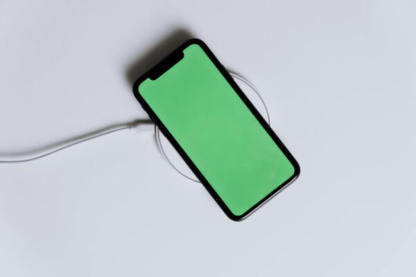 A minimalist smartphone with a green screen on a wireless charger, ideal for tech mockups