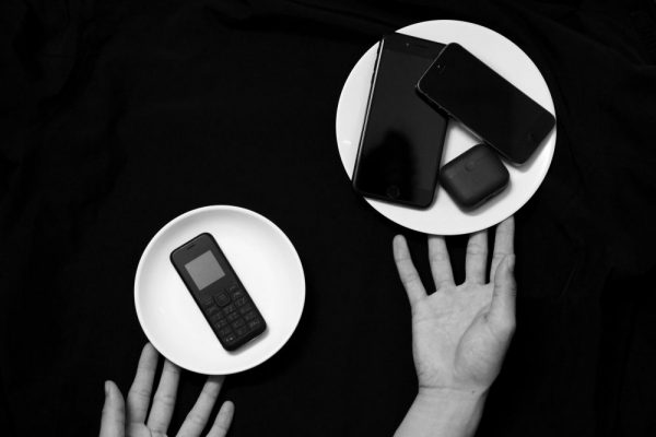 新手機資料搬家不完整?差異對照補救全指南 Contrasting old and new phones on plates in a minimalist black and white setup.