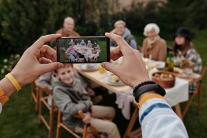 家長監護必備:孩子資料備份手機應用指南 A smartphone records a multi-generational family enjoying an outdoor meal together.