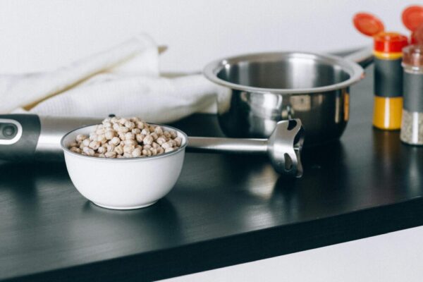 Bowl of chickpeas with cooking tools and spices on kitchen counter