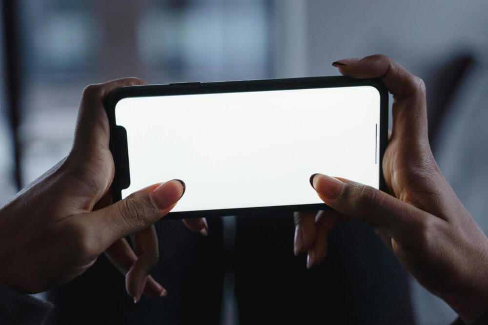 Close-up view of hands holding a smartphone with a blank white screen, perfect for mockup designs.