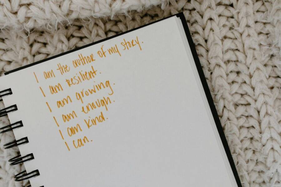 Notebook with handwritten affirmations on knitted fabric background