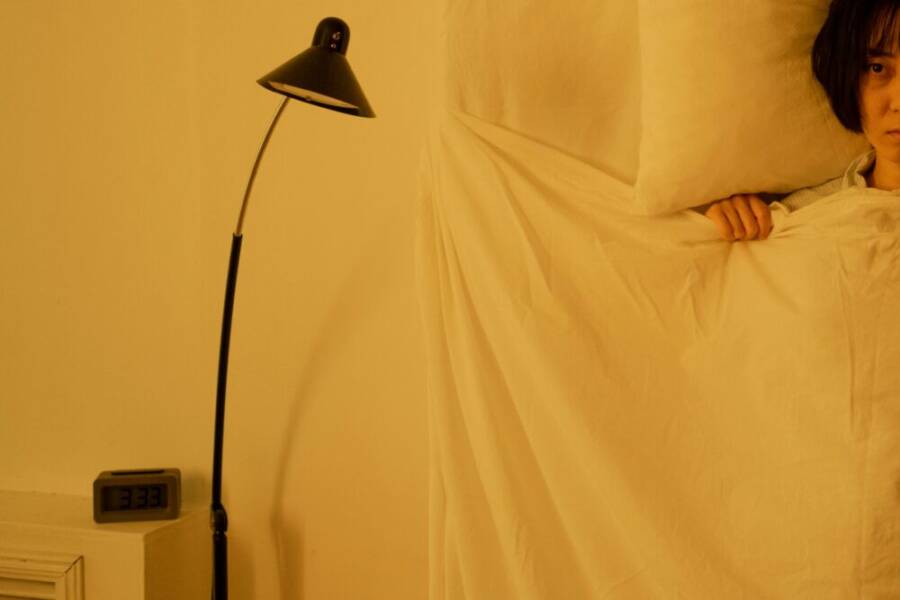 A woman lying awake in bed at 3:33 a.m., showcasing insomnia issues.