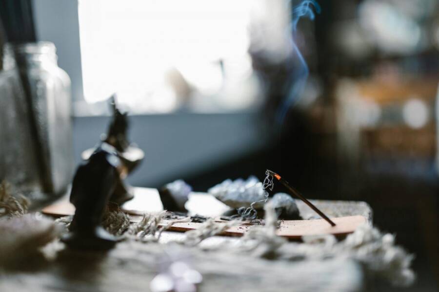 An incense stick burning on a table, creating a soothing atmosphere with gentle smoke.