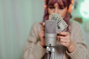 Adult woman with headset counting dollar bills in front of microphone indoors