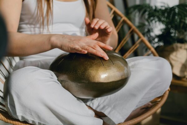 A person sits meditating, playing a handpan for relaxation and mindfulness.