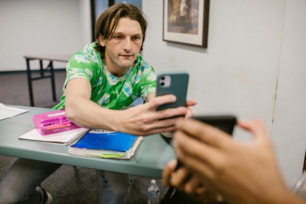 A student sharing his phone screen with another in a classroom setting