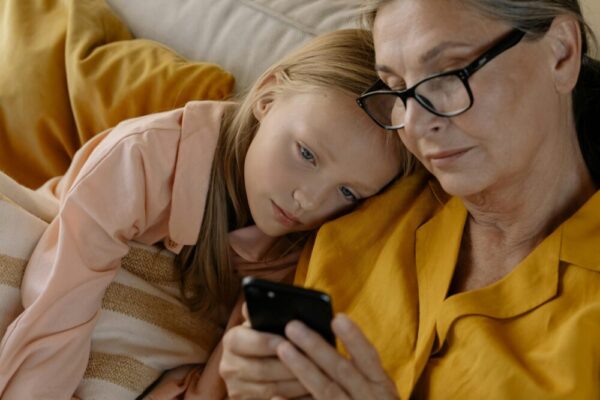 A grandmother and granddaughter sharing a bonding moment while looking at a mobile phone indoors