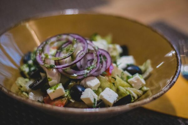 A mouth-watering Greek salad featuring fresh feta, black olives, and red onion rings.