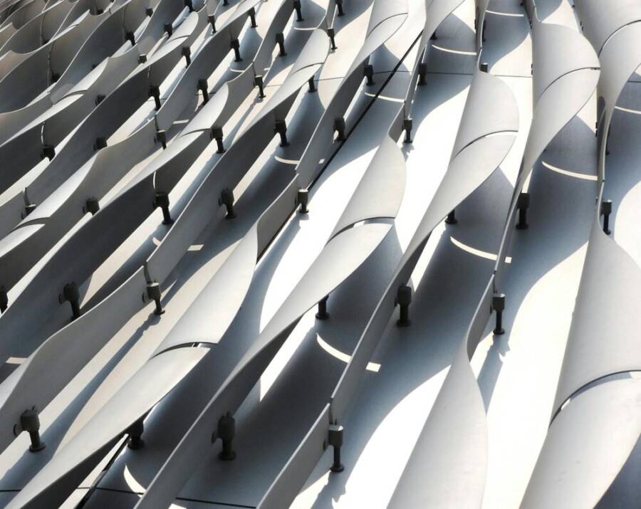 Abstract view of a contemporary architectural facade with curved metal elements in bright sunlight.