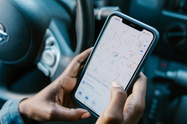 手機跨區 App 下載全攻略:區域切換與支付方法指南 Close-up of hands holding a smartphone with GPS navigation displayed, in a car setting.