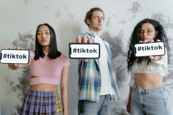 Group of young adults holding phones with social media apps indoors