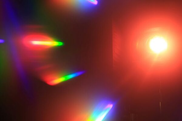 Lantern with bright glowing light placed in illuminated room with black walls and multicolored spectrum and refraction of shining light
