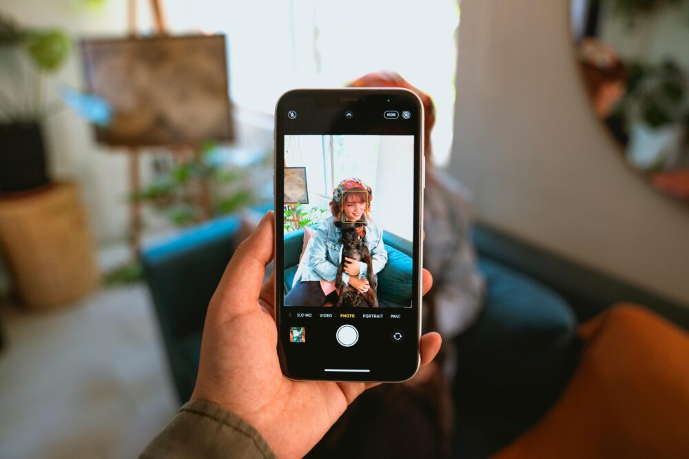 A woman holding her dog, captured through a smartphone indoors with modern decor.