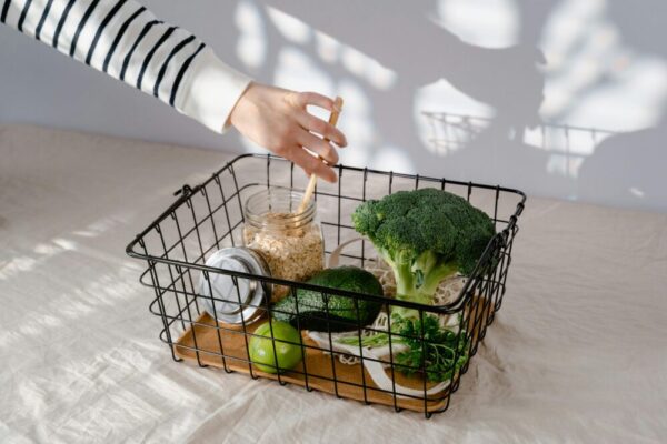 A hand reaches into a basket with fresh vegetables and grains, emphasizing healthy choices.