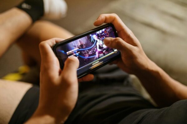 ROG Phone 8 對 RedMagic 9:遊戲手機效能對決 (ROG Phone 8 vs RedMagic 9:游戏手机性能对决) A person playing a mobile video game on a smartphone, focusing on gaming and technology lifestyle.