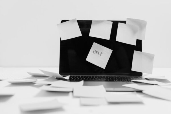 Monochrome image featuring sticky notes covering a laptop screen, symbolizing workplace chaos