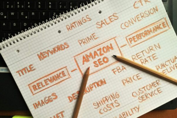 Notebook with handwritten Amazon SEO strategy topics highlighted on a keyboard.