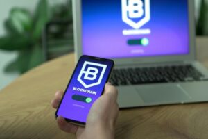 Web3 是什麼?如何改變你的日常生活 Person uses a blockchain application on smartphone, mirrored on laptop screen.