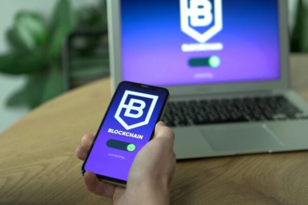 Person uses a blockchain application on smartphone, mirrored on laptop screen.