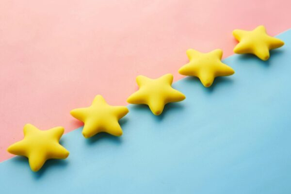 電商開店初期:蒐集第一批顧客回饋的實用策略 Yellow stars on pink and blue pastel background for rating or review concept.