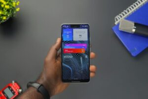 Close-up of a hand holding a smartphone displaying colorful notifications on a black surface
