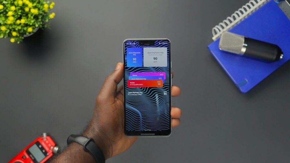 Close-up of a hand holding a smartphone displaying colorful notifications on a black surface