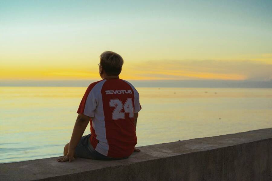 越南平順,一個男子坐在海邊,觀賞寧靜的日落。