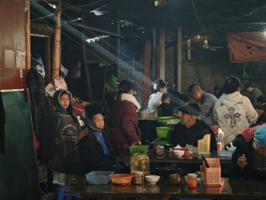 室內市場裡熱鬧非凡，形形色色的人們在木桌旁吃飯、交流。