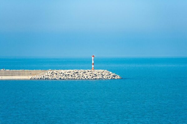 在蔚藍的天空和平靜的大海下，防波堤上的燈塔，非常適合海洋主題。