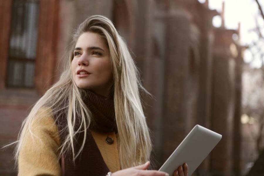 擁有銀色ipad的棕色裙子的女人
