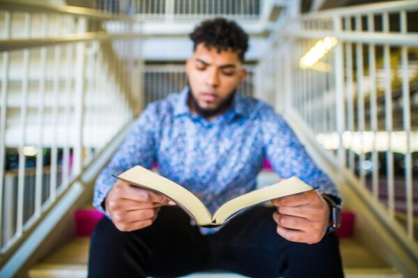 一位年輕男子熱衷於在室內樓梯上看書，營造出學習的氛圍。