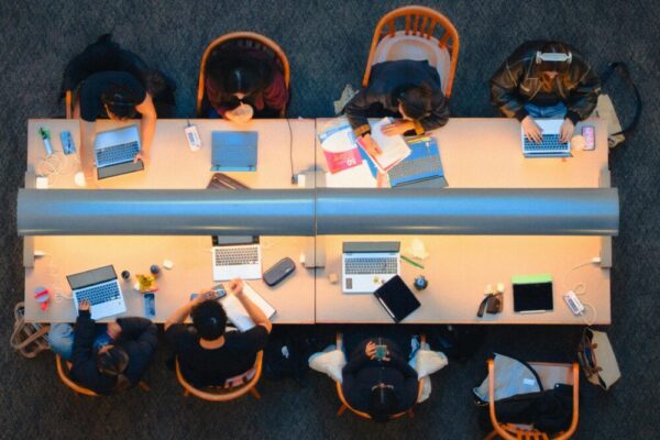 這是從空中拍攝的加拿大省金斯頓市圖書館的一張桌子旁，一群學習小​​組正在使用筆記型電腦的畫面。